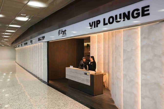 The entrance to the BRT VIP Lounge at Tancredo Neves International Airport features a reception desk staffed by two attendants.