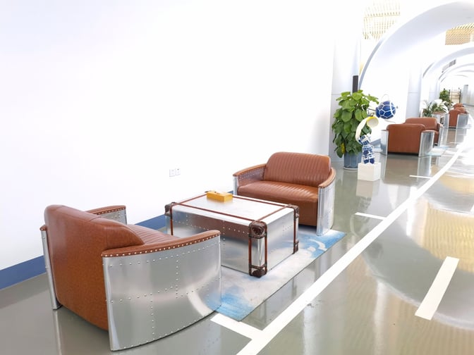 Seating area in Tangshan Sannühe Airport's First Class Lounge features metal-framed chairs and a table, with decorative plants nearby.