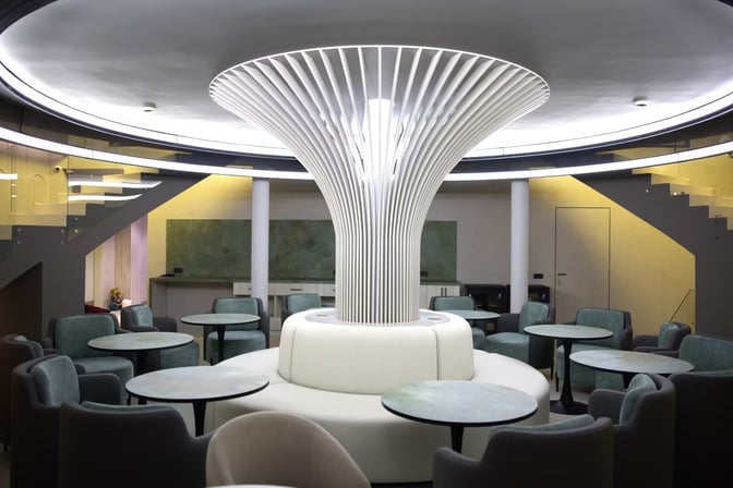 The seating area in the Anjir Business Lounge at Tashkent International Airport features circular tables and cushioned chairs around a central structure.