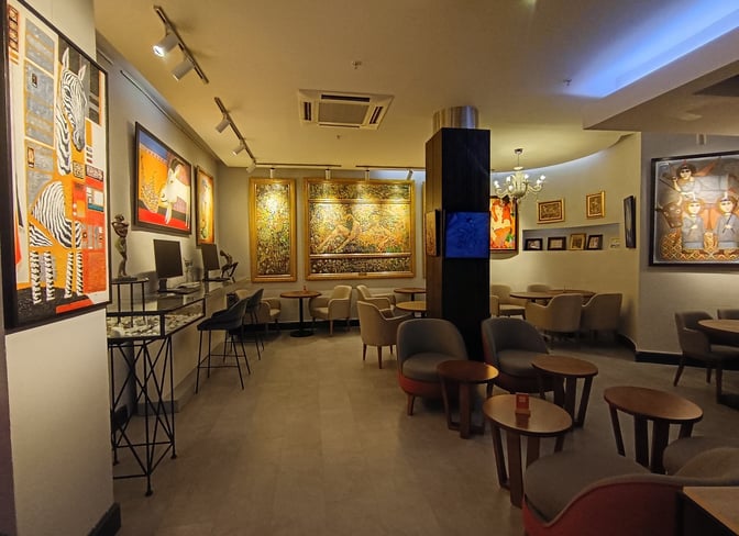 The Primeclass CIP/VIP Lounge at Tbilisi International Airport features a seating area with tables and chairs, surrounded by artwork.