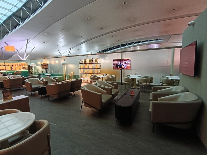 The Primeclass CIP/VIP Lounge at Tbilisi International Airport features comfortable seating areas with tables and a television for entertainment.