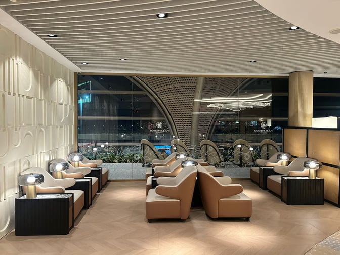 Seating area at Plaza Premium Lounge, Techo International Airport, features individual chairs with side tables and lamps, offering airport views.