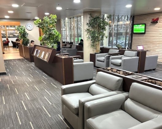 The seating area in Salones VIP Pacific Club at Temuco Airport features comfortable chairs, reading materials, and a view of the tarmac.