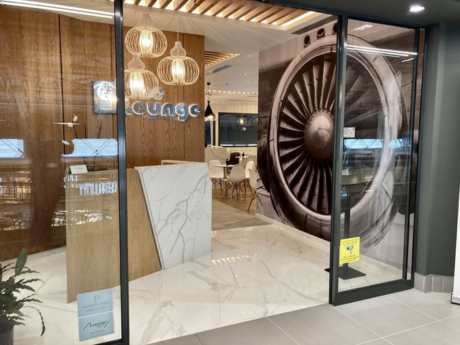 The entrance to The Lounge Thessaloniki at Thessaloniki Makedonia International Airport features a reception desk and seating area visible inside.
