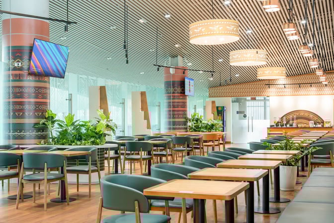 The SH Premium Lounge at Tho Xuan Airport features spacious seating with tables and a self-serve beverage area.