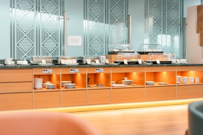 The buffet area at SH Premium Lounge Tho Xuan offers a variety of covered dishes and plates for self-service dining.