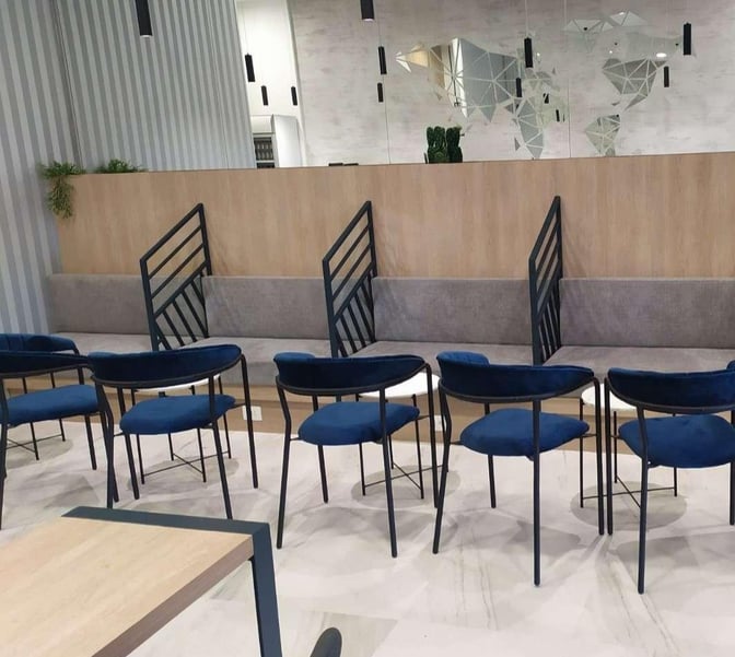 The seating area in Tivat Airport's Business Lounge features cushioned benches with partitioned sections and chairs arranged around small tables.