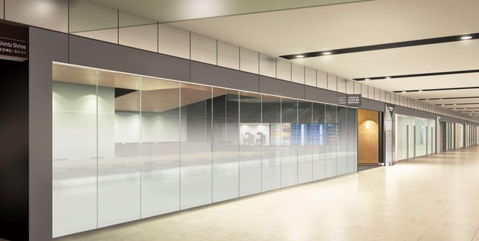 The entrance to POWER LOUNGE CENTRAL at Tokyo International Airport features glass walls and is located along a spacious corridor.