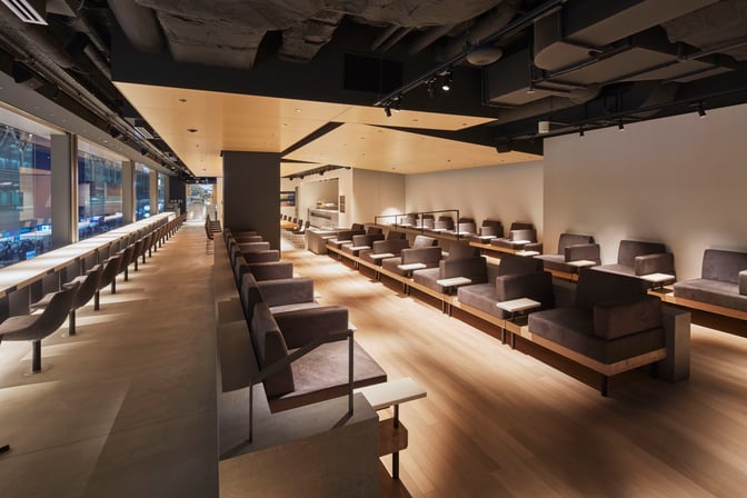 The POWER LOUNGE CENTRAL at Tokyo International Airport features spacious seating with individual tables and a view of the terminal.