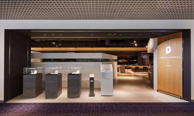 The entrance to POWER LOUNGE NORTH at Tokyo International Airport features display cases and signage, leading to a seating area inside.