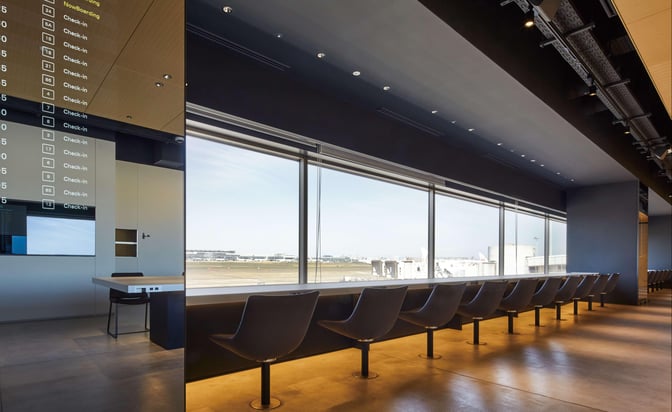 The seating area in POWER LOUNGE SOUTH at Tokyo International Airport offers counter seating with expansive views of the runway.