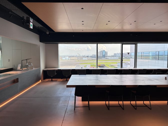 The POWER LOUNGE PREMIUM at Tokyo International Airport features a spacious seating area with large windows offering runway views.