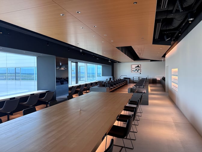 The POWER LOUNGE PREMIUM at Tokyo International Airport features spacious seating with tables and chairs, offering views of the tarmac.