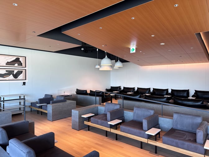 The POWER LOUNGE PREMIUM at Tokyo International Airport features tiered seating with individual tables, providing a comfortable waiting area for travelers.