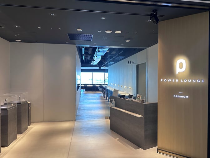 The entrance to POWER LOUNGE PREMIUM at Tokyo International Airport features a reception desk and leads to a seating area.