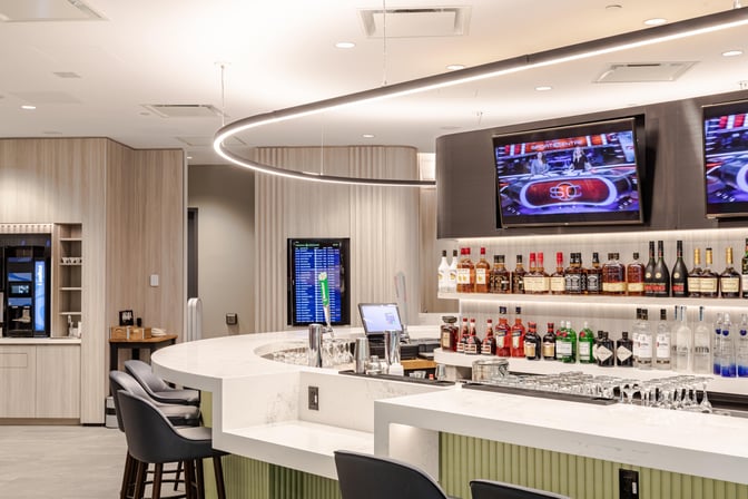 The Plaza Premium Lounge bar at Toronto Pearson Airport offers a selection of spirits and seating with flight information displays.