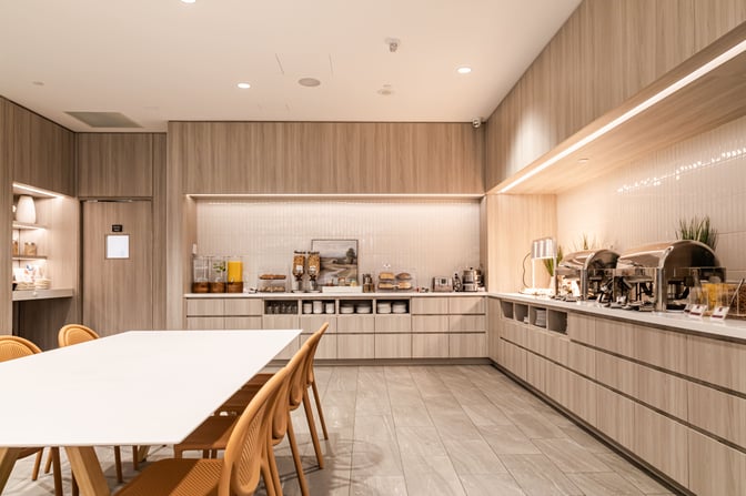 The Plaza Premium Lounge at Toronto Pearson International Airport features a self-serve food area with buffet stations and seating.