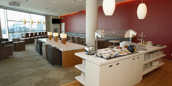 The Plaza Premium Lounge at Toronto Pearson offers a self-serve food station with seating areas overlooking the airport tarmac.