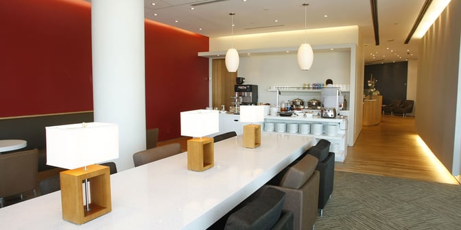 The Plaza Premium Lounge at Toronto Pearson features a self-serve food area with seating and a long communal table.