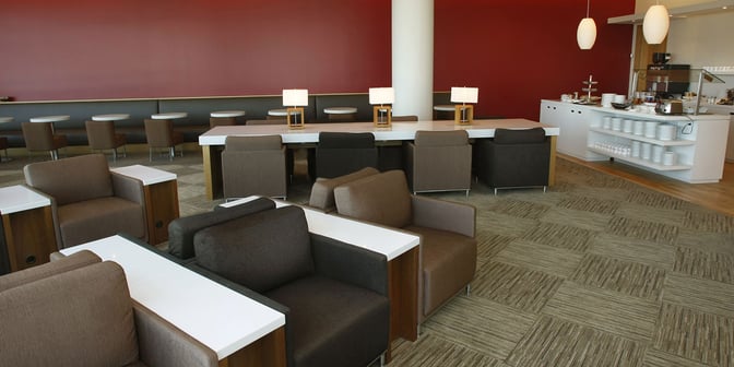 The Plaza Premium Lounge at Toronto Pearson International Airport features comfortable seating, a communal table with lamps, and a self-serve dining area.