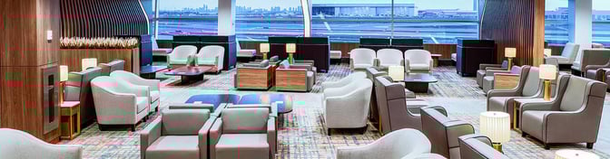 The seating area in Plaza Premium Lounge at Toronto Pearson Airport offers comfortable chairs and tables with views of the runway.