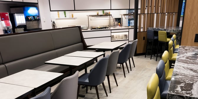 The dining area at Plaza Premium Lounge in Toronto Pearson Airport features booth seating and a self-serve beverage station.