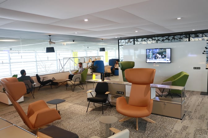 The seating area at La Croix Du Sud lounge in Toulouse Blagnac Airport features comfortable chairs and a television for passenger relaxation.