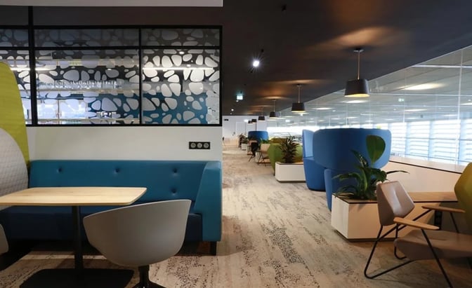 The seating area in La Croix Du Sud lounge at Toulouse Blagnac Airport features booth seating and individual chairs with tables.