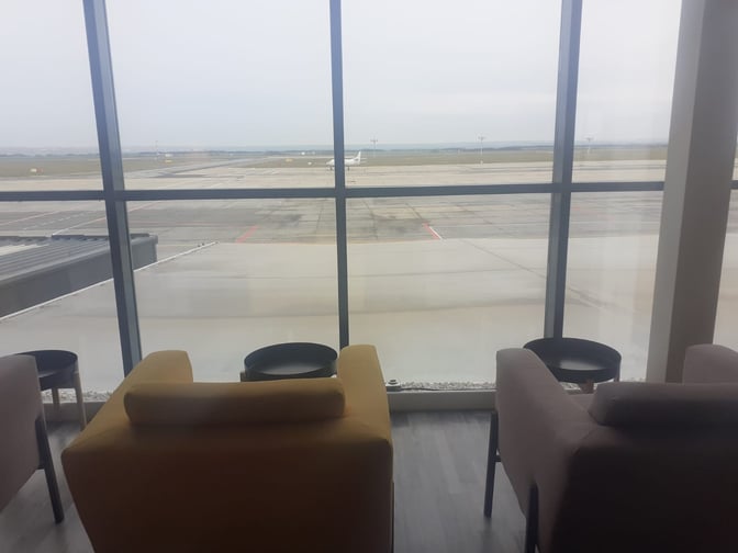 Seating in the Horizons Lounge at Traian Vuia International Airport offers views of the runway through large windows.