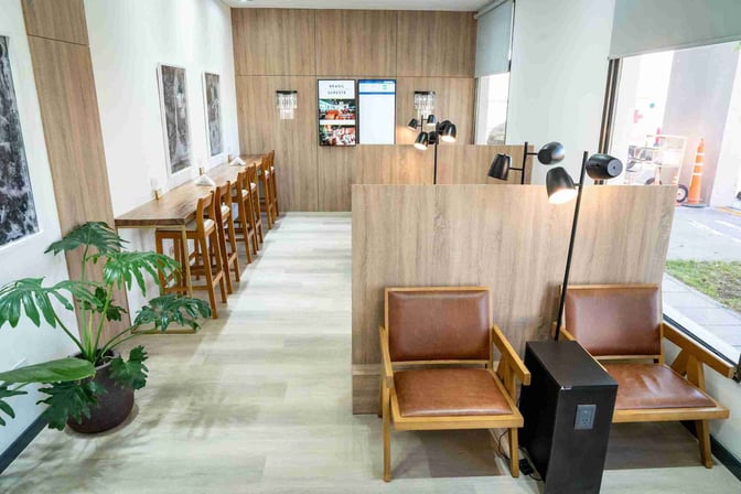 The W Lounge Trelew features a seating area with individual chairs and a counter with stools, offering workspaces and charging stations.