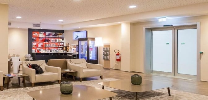 The seating area in Sala Calligaris at Trieste Friuli Venezia Giulia Airport features comfortable chairs and a coffee station with Illy products.