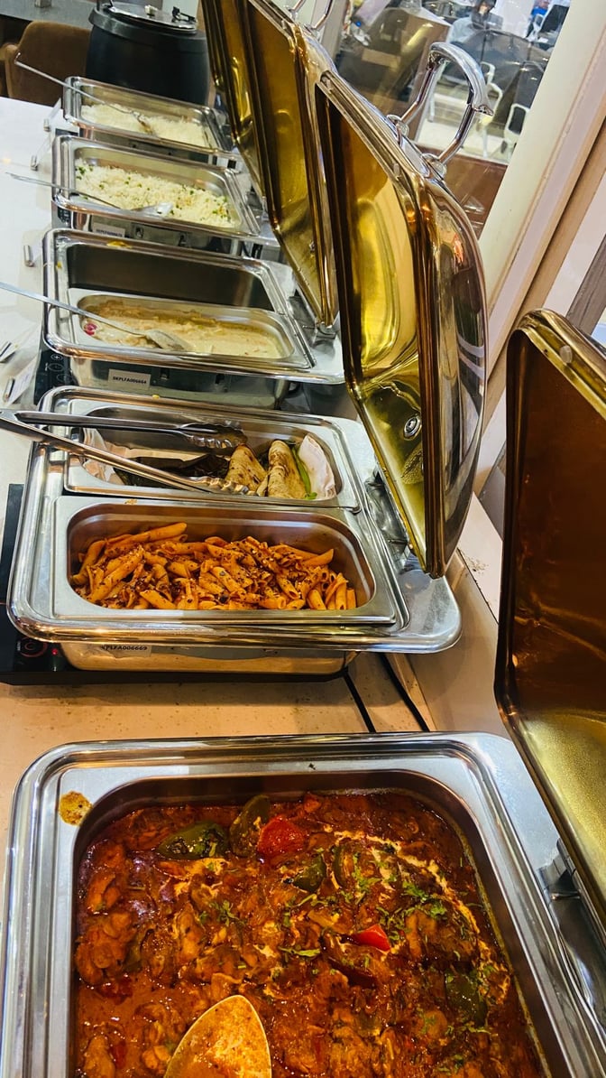 The buffet area at Thiruvananthapuram International Airport's lounge offers a variety of hot dishes in self-serve chafing dishes.
