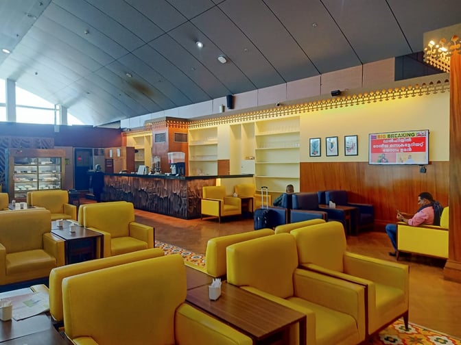 The lounge at Thiruvananthapuram International Airport features comfortable seating and a service counter with refreshments and snacks available.