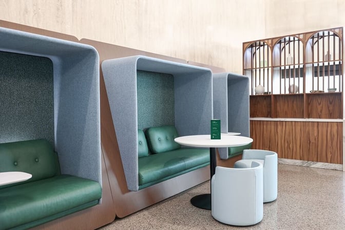 Booth seating at the Escape Lounge in Tulsa International Airport offers semi-private spaces with tables and cushioned seats.