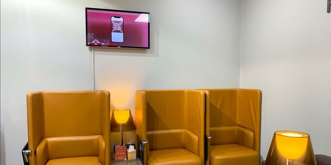 The seating area in Hayyak Lounge at Turaif Domestic Airport features high-backed chairs with a side table and a lamp.