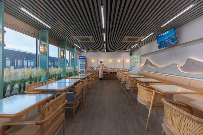 The SH Premium Lounge at Tuy Hoa Airport features a dining area with tables, chairs, and a self-serve beverage station.
