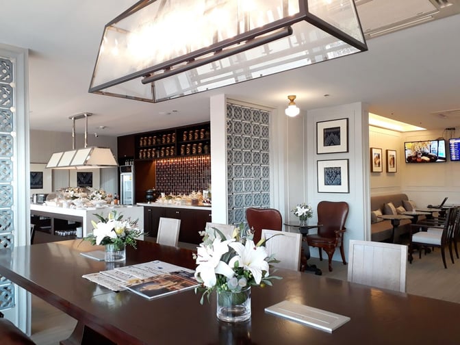 The Coral Executive Lounge at Udon Thani International Airport features a self-serve food area and seating with tables and chairs.