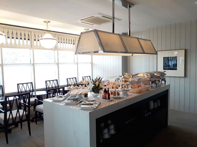 Self-serve buffet area in The Coral Executive Lounge at Udon Thani International Airport offers a variety of covered dishes and utensils.