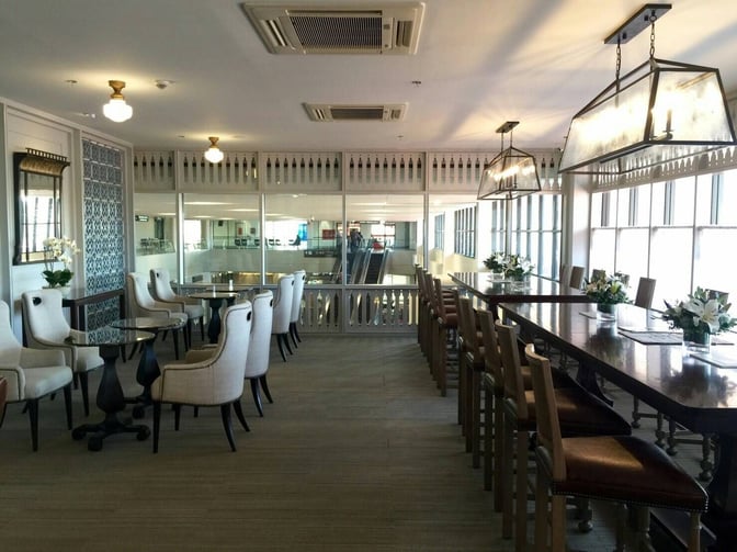 The Coral Executive Lounge at Udon Thani International Airport features a seating area with tables, chairs, and high-top counters for dining.