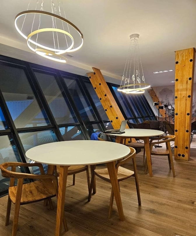 The seating area in W Lounge Ushuaia features round tables and chairs near large windows, providing a view of the airport.
