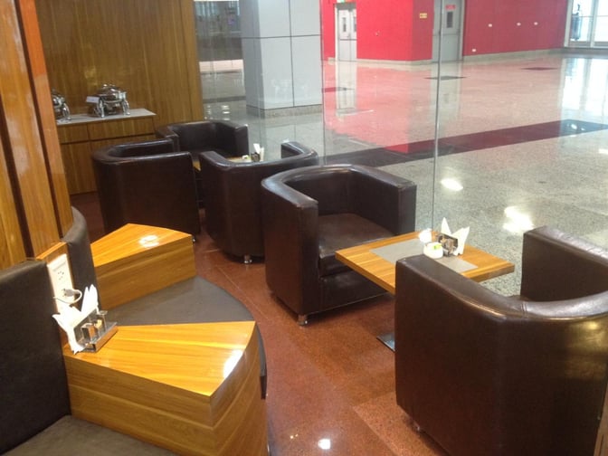 Seating area in the Premium Lounge at Vadodara Airport features comfortable chairs and small tables, ideal for relaxation and dining.