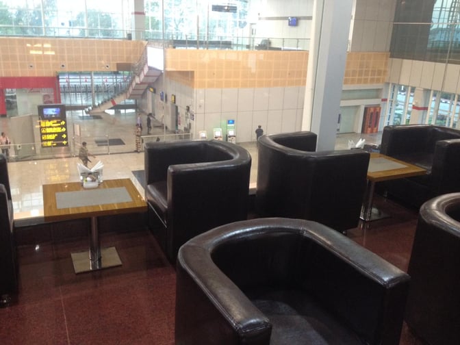 Seating area in the Premium Lounge at Vadodara Airport offers comfortable chairs and tables overlooking the terminal below.