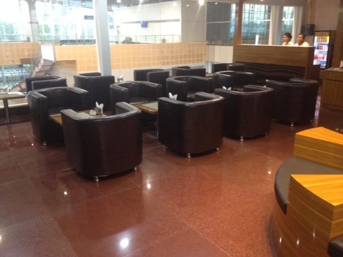 The seating area in Vadodara Airport's Premium Lounge features individual armchairs and small tables, providing a comfortable space for travelers.