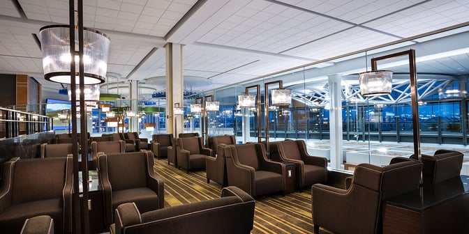 The seating area in Plaza Premium Lounge at Vancouver International Airport offers comfortable armchairs with individual tables and airport views.