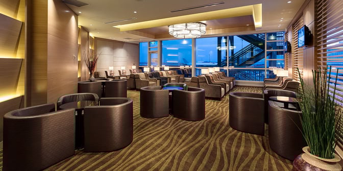 The Plaza Premium Lounge at Vancouver International Airport features spacious seating with individual tables and views of the airport tarmac.