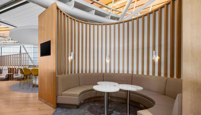 Curved booth seating in SkyTeam Lounge at Vancouver International Airport offers semi-private spaces with small tables and integrated lighting.