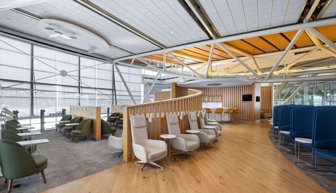 The SkyTeam Lounge at Vancouver International Airport features diverse seating options, including individual chairs and booths, with adjacent tables for convenience.