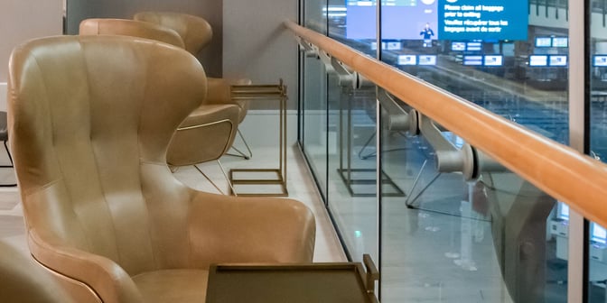 Seating area at Plaza Premium US Transborder Lounge in Vancouver International Airport features comfortable chairs with individual side tables overlooking the terminal.