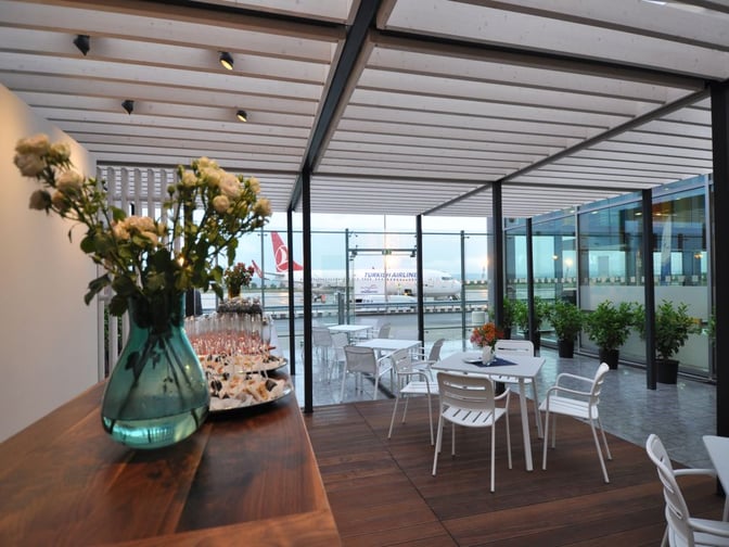 The outdoor seating area at Varna Airport's VIP Lounge offers tables with views of the tarmac and nearby aircraft.