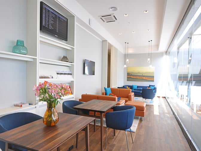 The Varna Airport VIP/Business Lounge features comfortable seating areas with tables, a flight information screen, and reading materials.